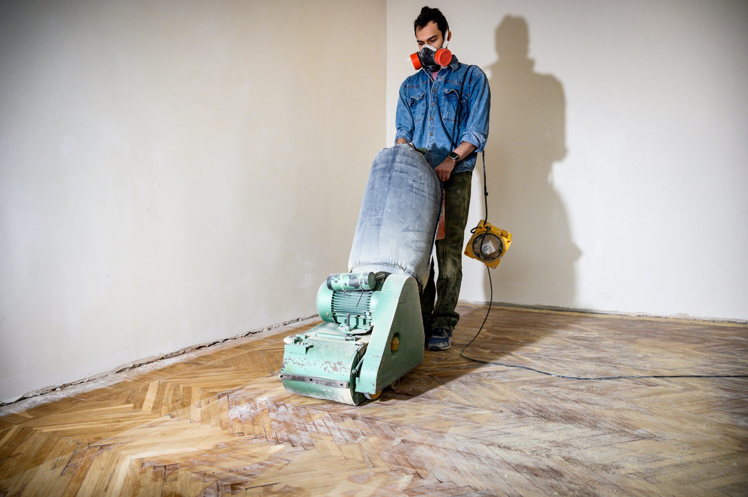 Parquet Floor Sanding in Finchley with technician using a drum sander on an oak herringbone parquet floor during restoration.