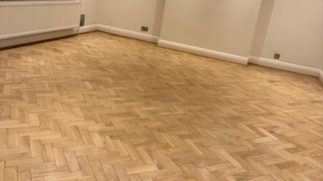 Parquet Floor Sanding in Finchley on a freshly restored oak herringbone parquet floor in an empty living room.