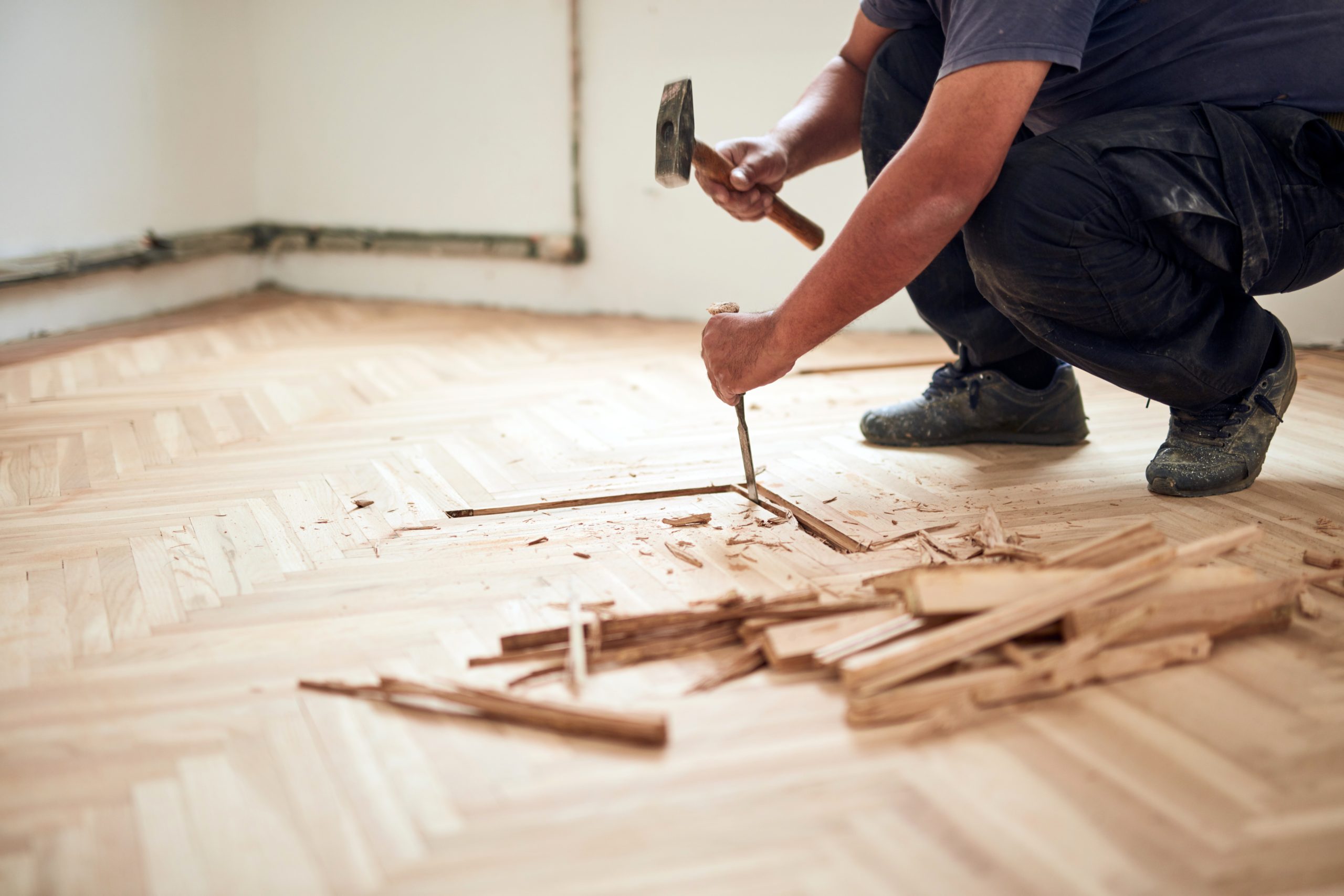 Wood Floor Sanding in Finchley – technician repairing damaged light oak herringbone parquet flooring before sanding and refinishing.