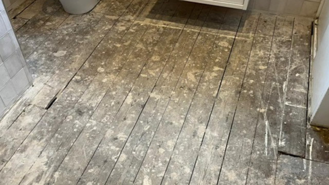 Wood Floor Sanding in Finchley – heavily worn bathroom pine floorboards with paint splashes and gaps before restoration.
